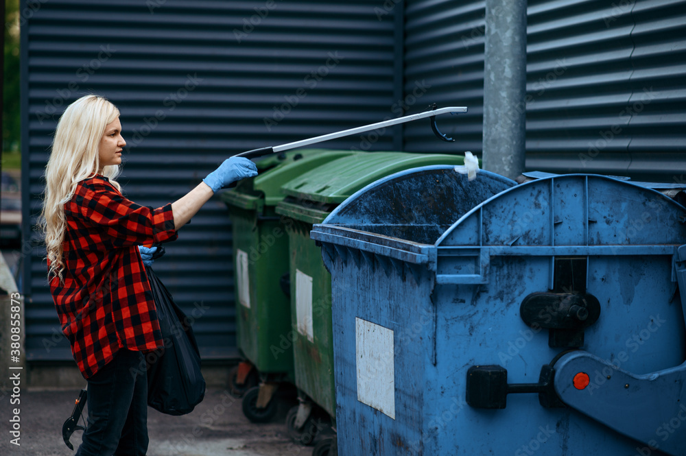 Volunteer puts plastic trash bag into the bin Volunteer puts plastic trash bag into the bin