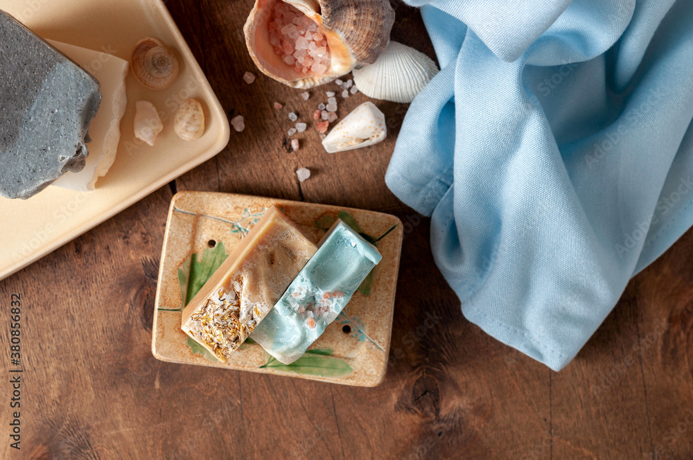 Natural handmade soap bar in ceramic soap dish with spa accessories on wooden table