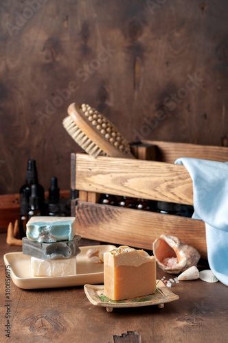 Natural handmade soap bar in ceramic soap dish with spa accessories on wooden table