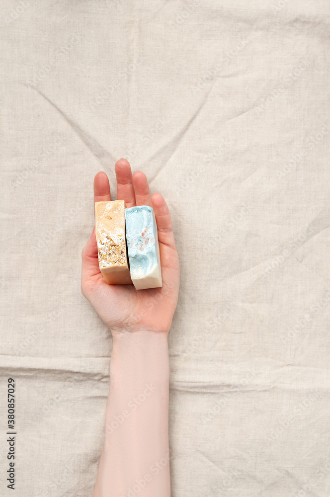 Woman holding natural handmade soap bar on linen fabric background
