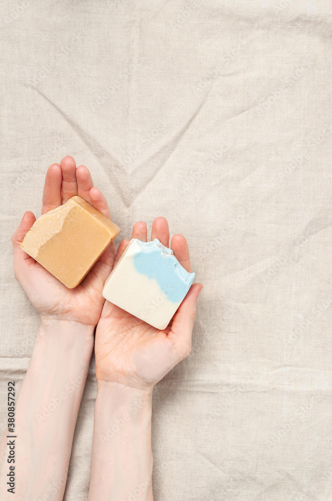 Woman holding natural handmade soap bar on linen fabric background