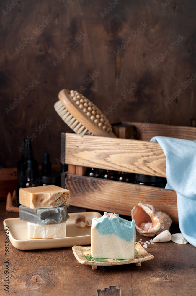 Natural handmade soap bar in ceramic soap dish with spa accessories on wooden table