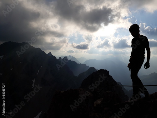 Berggipfel, Silhouette mit dunkler Wolkenstimmung und Sonnenstrahlen.