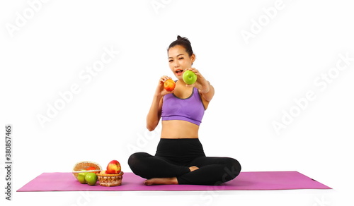 Asian slim woman in sport wear sitting on yoga mat smiling showing the apples in hands isolate on white background , diet healthy lifestyle concept
