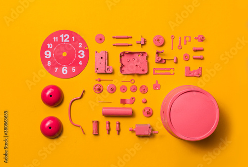 Organised Disassembled Clock/pink parts on orange background