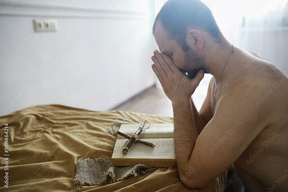 Man reading and pray from the holy bible near the bed in the evening. Christians and Bible study concept. Studying the Word Of God in church.