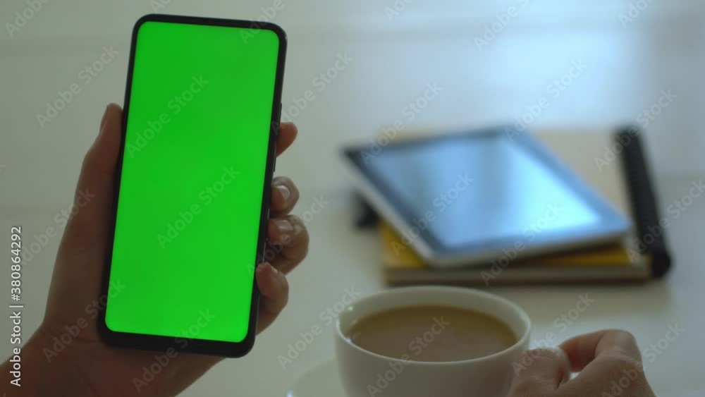 Handheld Camera: business woman using smartphone viewing green screen on mobile phone browsing chroma key online watching enjoying drinking coffee reading social media close up hands Handheld Camera: business woman using smartphone viewing green screen on mobile phone browsing chroma key online watching enjoying drinking coffee reading social media close up hands
