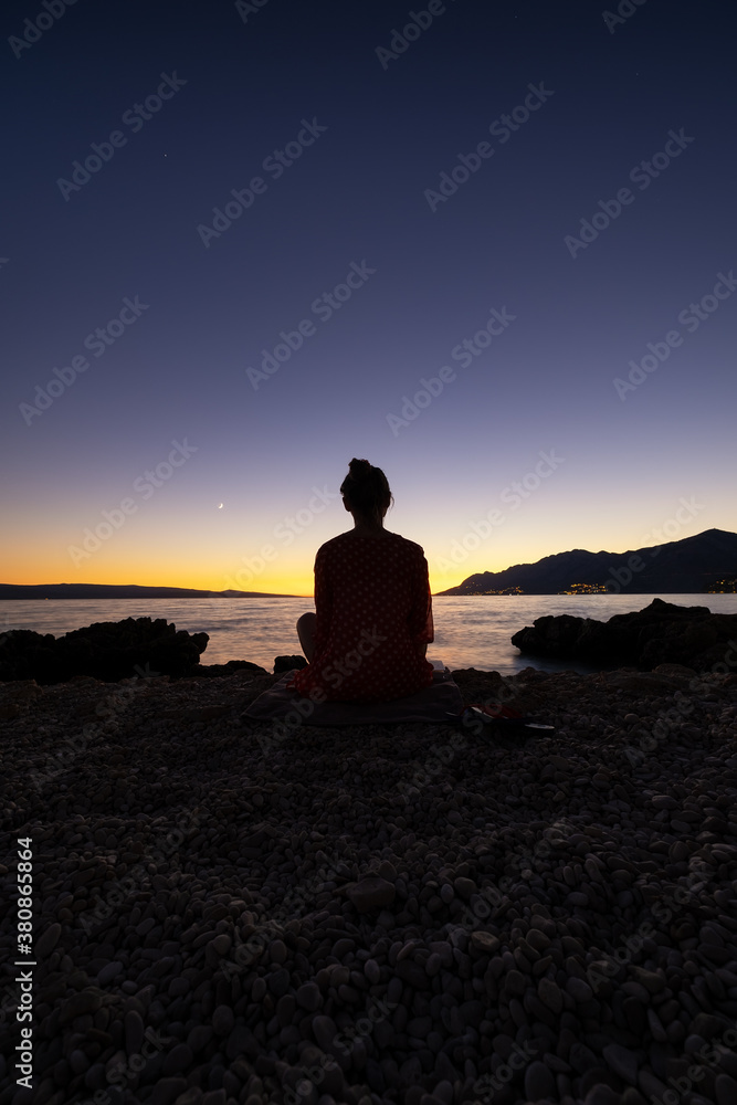 Silhouette girl on the sky background during sunset. Yoga and meditation. A place for rest and relaxation. Landscape in summer time. Mediterranean Sea.