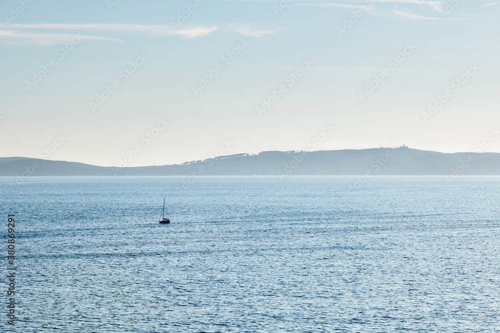 A lonely boat sails away from Ons Island in the Ria de Pontevedra in Galicia at dusk.