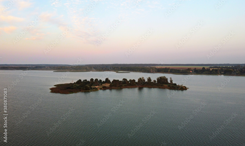 A view from the sky to a small forest island without anyone in a large lake