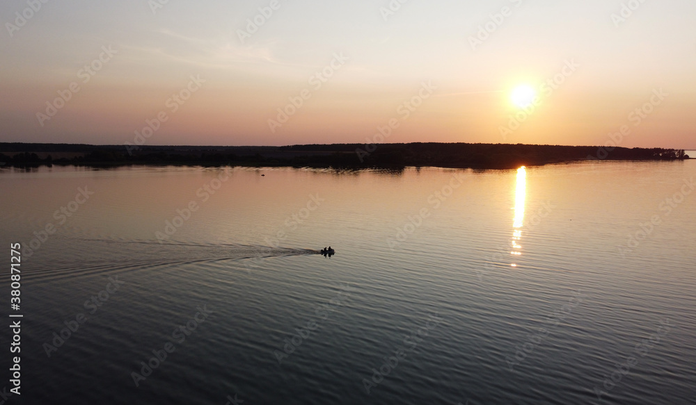 Top view of small fishing boat with fishermen at sunset on the lake
