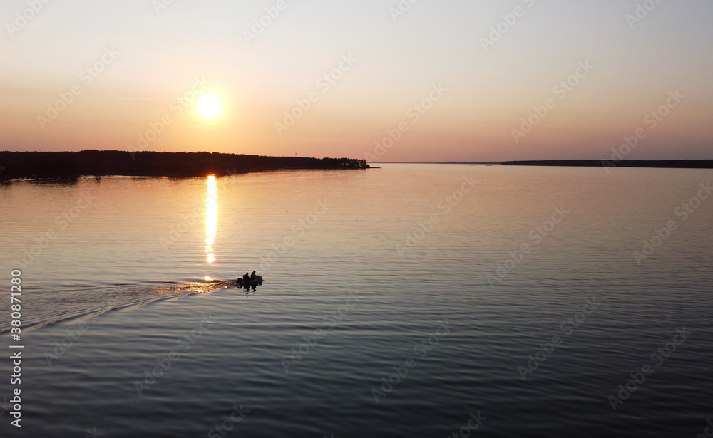 Top view of small fishing boat with fishermen at sunset on the lake Top view of small fishing boat with fishermen at sunset on the lake