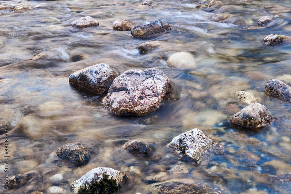 Obraz premium natural background - stones in a rapid mountain stream, the water is blurred in motion
