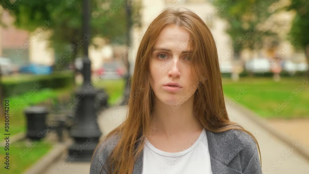 A young Caucasian charismatic blonde with long hair and braces on her teeth looks down at the ground and then gazes into the camera. Calm emotions. Summer evening. A young Caucasian charismatic blonde with long hair and braces on her teeth looks down at the ground and then gazes into the camera. Calm emotions. Summer evening.