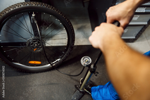 Bicycle assembly in workshop, man inflates wheel