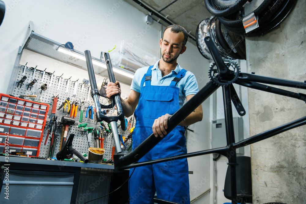 Bicycle assembly in workshop, man installs fork Bicycle assembly in workshop, man installs fork