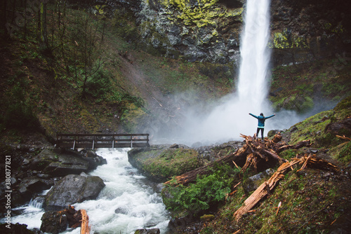 Young woman exploring a beautiful waterfall on a hike. photo