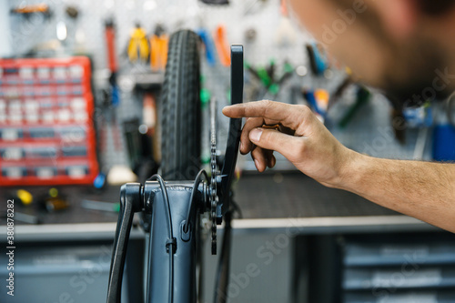 Bicycle assembly in workshop, man setting up chain