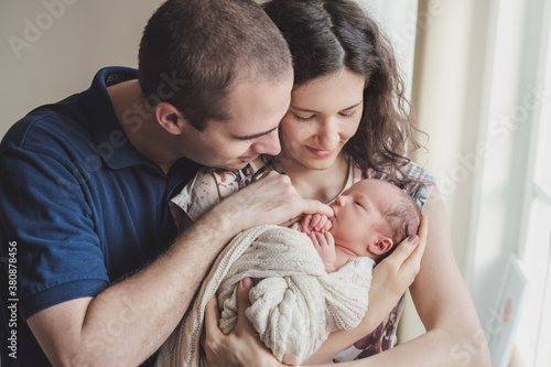 Newborn baby in his parents' arms sucking on his father's little finger