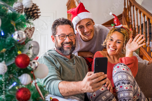 Happy family at home during christmas eve day enjoy a video phone call with friends and parents - concept of happy people and online internet technology - people and modern lifestyle having fun