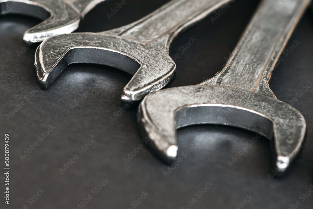 Closeup set of chrome wrenches or spanners isolated on gray table in workshop. Silver wrenches. Mechanic tools. Hardware for service technician to fix and maintenance. Closeup set of chrome wrenches or spanners isolated on gray table in workshop. Silver wrenches. Mechanic tools. Hardware for service technician to fix and maintenance.
