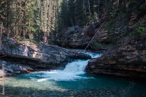 A small waterfall pours over a shale ledge in a forest photo