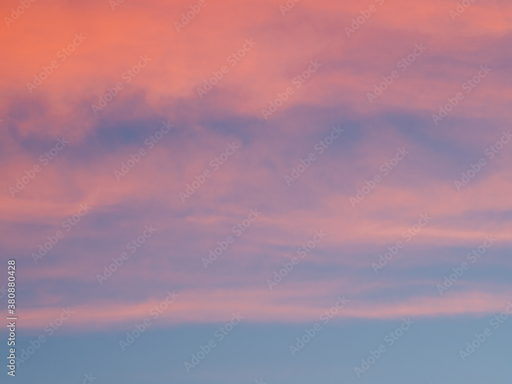 Bright sky illuminated by pink sunset light blurred clouds as background and texture