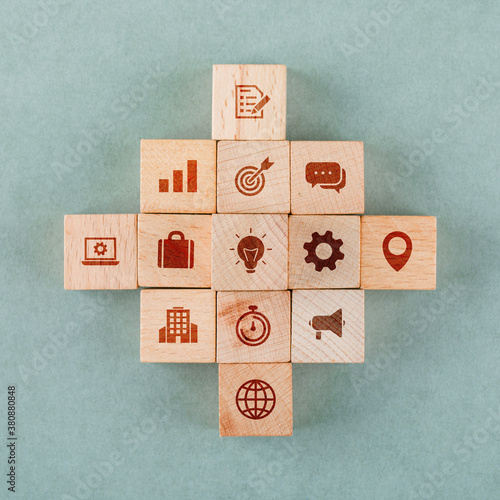 Business strategy concept with wooden blocks with icons on sage color background flat lay. horizontal image
