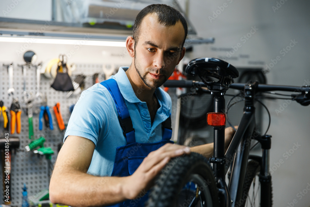 Bicycle repair in workshop, man checks the tires Bicycle repair in workshop, man checks the tires