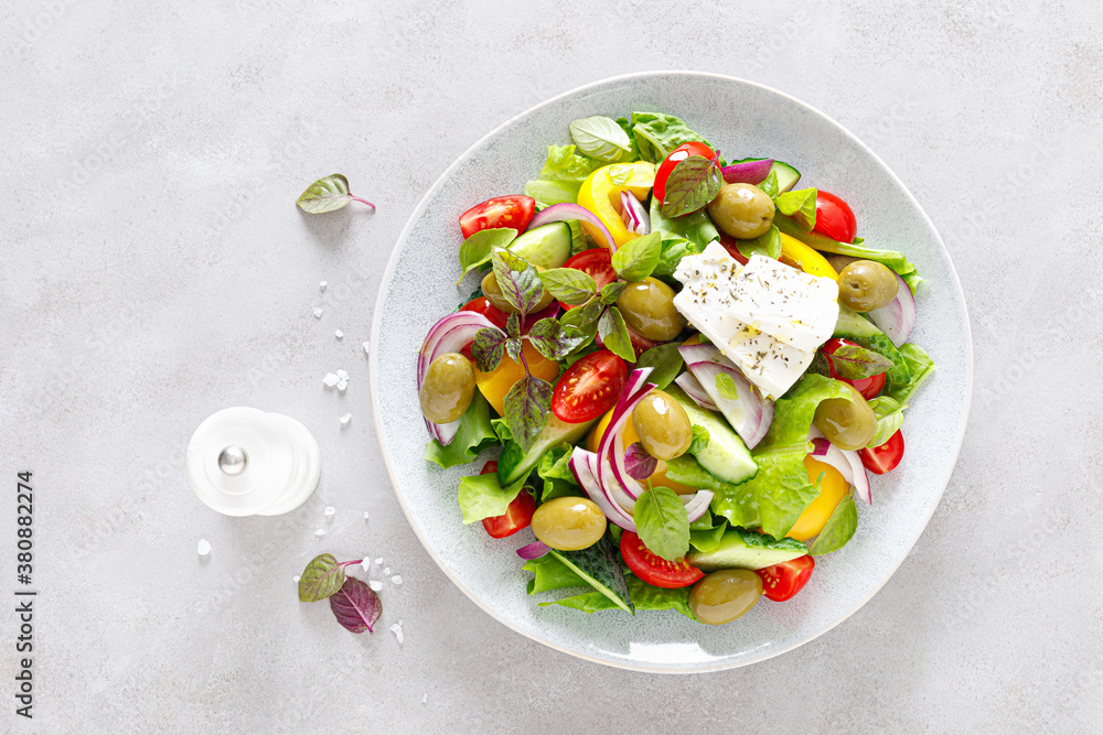 Greek salad. Fresh vegetable salad of cucumbers, tomatoes, olives, onion, bell pepper, feta cheese, lettuce and herbs and dressed with salt, pepper and olive oil. Horiatiki salad Greek salad. Fresh vegetable salad of cucumbers, tomatoes, olives, onion, bell pepper, feta cheese, lettuce and herbs and dressed with salt, pepper and olive oil. Horiatiki salad