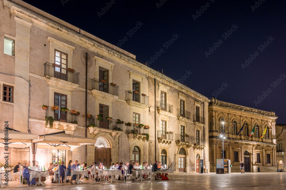 Platz in Ortygia auf Sizilien bei sternenklaren Nachthimmel mit belebten Straßencafé