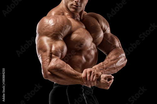 Foto Muscular man showing muscles and biceps isolated on black background
