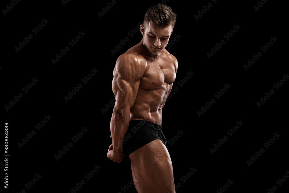 Muscular man showing muscles isolated on black background. Strong male naked torso abs