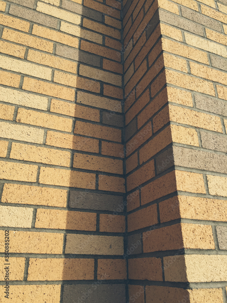 Beige and brown brick wall, casting shadow Beige and brown brick wall, casting shadow