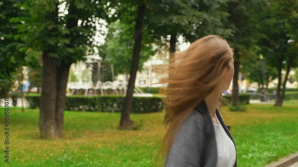 Young caucasian charismatic blonde woman with long hair and braces on her teeth is dancing and having fun on the park alley. Positive emotions. Summer evening. Young caucasian charismatic blonde woman with long hair and braces on her teeth is dancing and having fun on the park alley. Positive emotions. Summer evening.