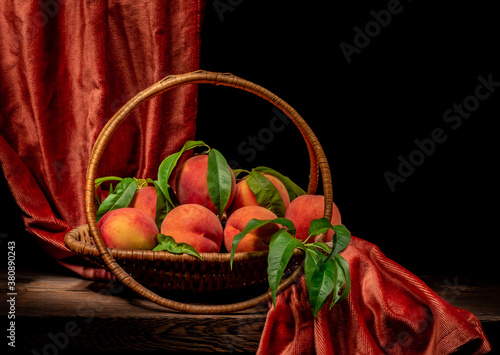 wicker basket with beautiful peaches over black background