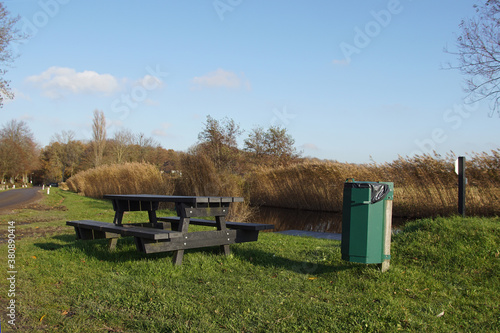 Wooden bench and table in the grass along a road and a ditch with reed in the autumn near the Dutch village of Bergen. November, The Netherlands. © Thijs de Graaf