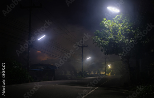 Fototapeta Empty road underneath street light at night with UFO on back