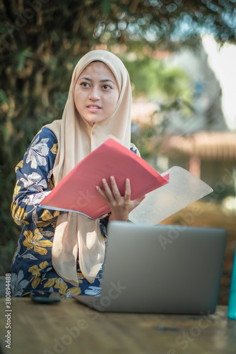 Photo of islamic female student wearing headscarf with laptop