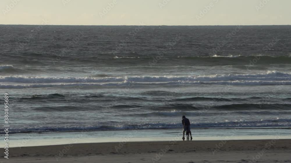 Parent and child playing by the water in Cannon Beach Oregon around sunset. Parent and child playing by the water in Cannon Beach Oregon around sunset.