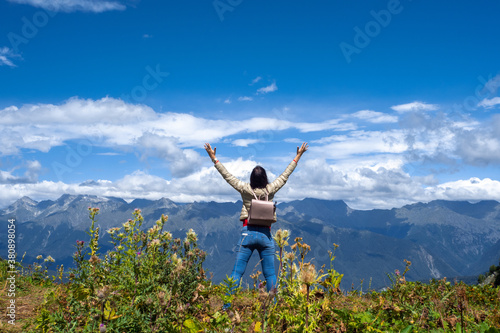 Unity with nature, a young female tourist in the mountains. Arms out to hug the horizon.