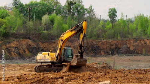 Earth moving equipment. Yellow excavator digging the ground. Excavator bucket scoops up the soil on nature background. Slow motion.