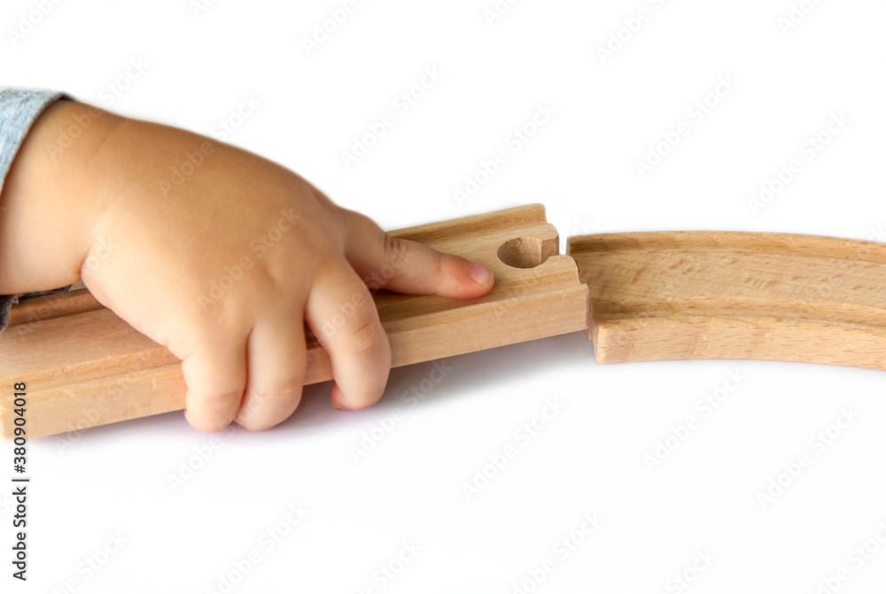 A child builds a railway out of wood. Close-up of a child's hand.