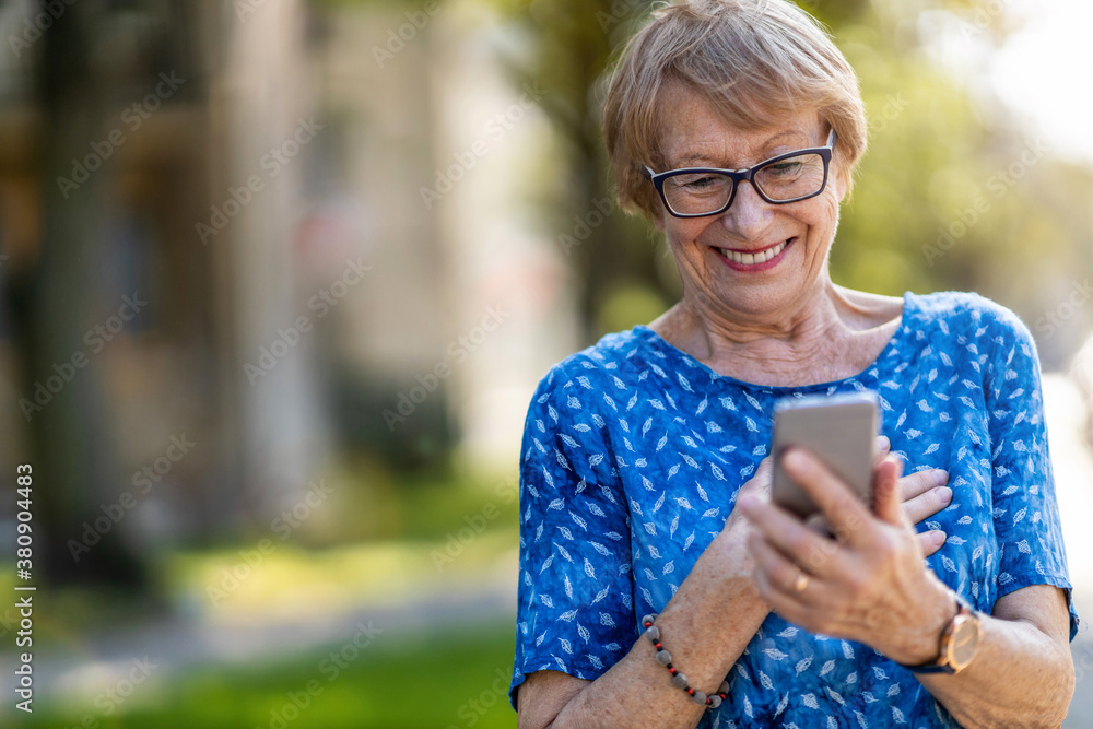 Happy senior woman using mobile phone outdoors
