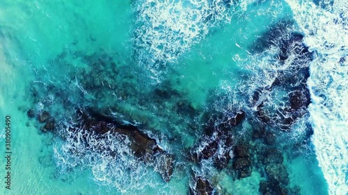 4k aerial drone shot of beautiful tropical blue ocean with waves breaking on rocks photo
