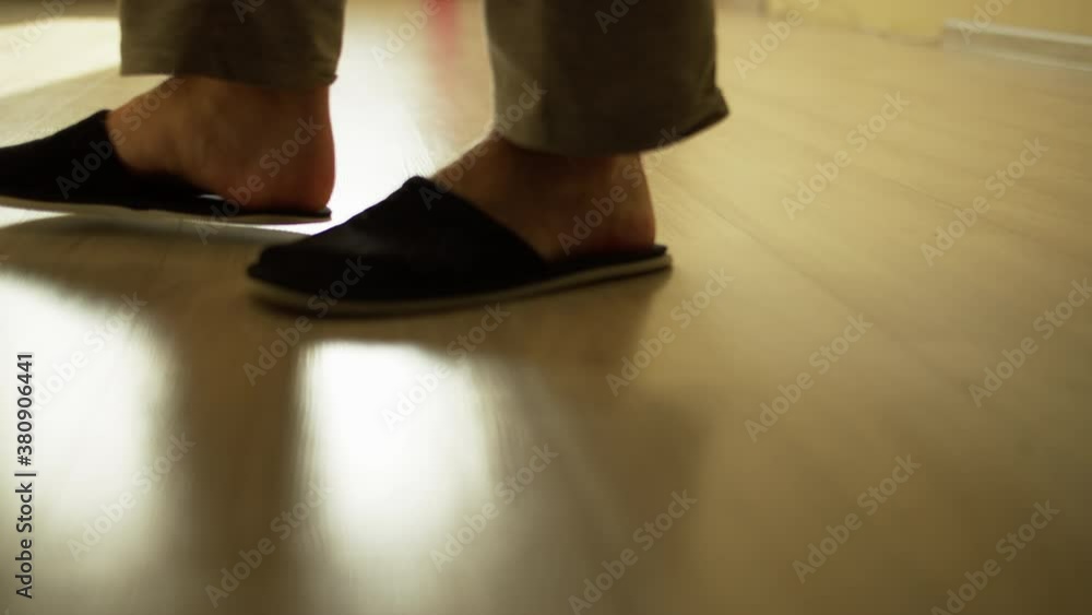 A man in slippers walks on a light floor, camera tracking A man in slippers walks on a light floor, camera tracking