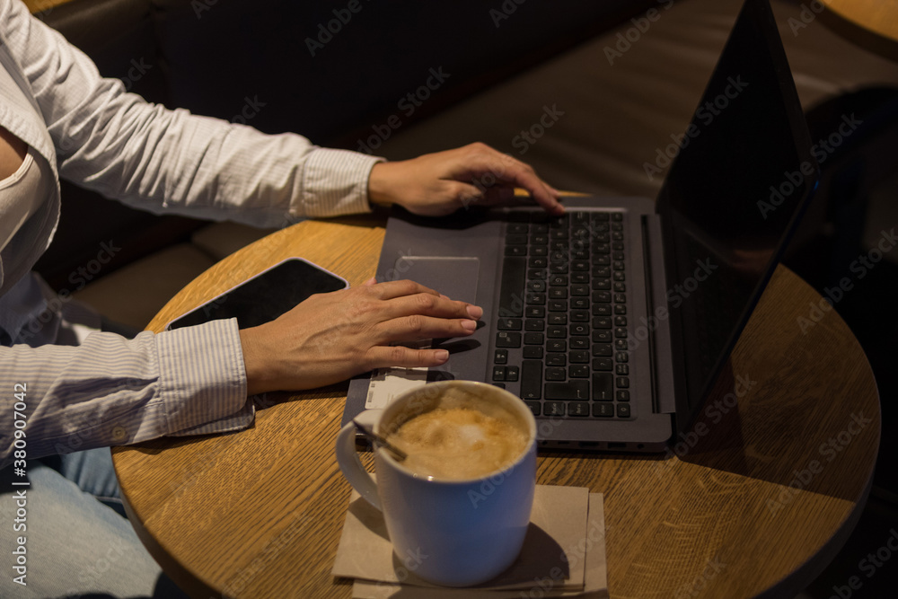Laptop on a wooden table in a coffee shop with a cup of coffee Laptop on a wooden table in a coffee shop with a cup of coffee