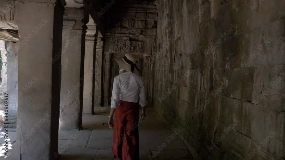 Beautiful woman walking through ancient ruins of old stone temple in Cambodia Beautiful woman walking through ancient ruins of old stone temple in Cambodia