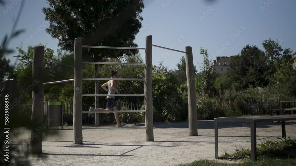 A man running through a park full of gym equipment in slow motion during a workout.