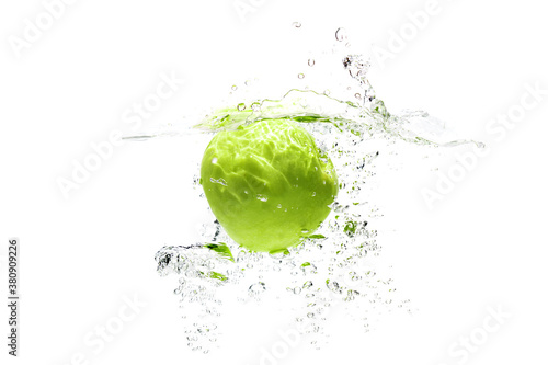 one green apple falling into water on a white background with splashes  drops and bubbles.